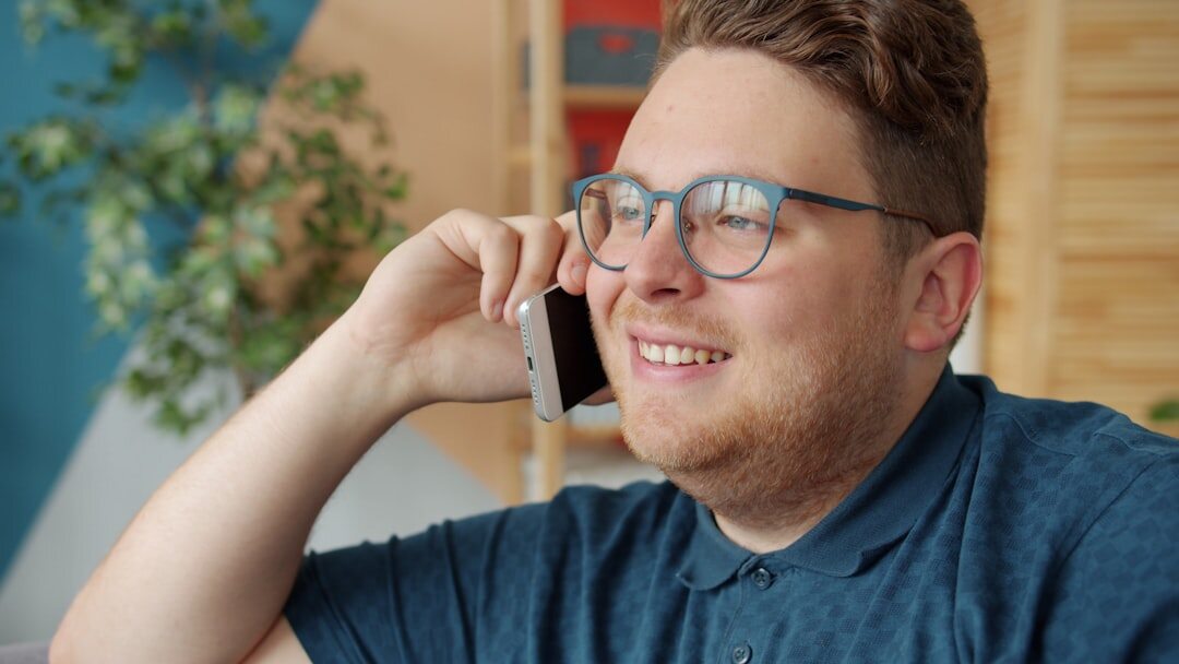 Person smiling while talking on the phone in a bright room