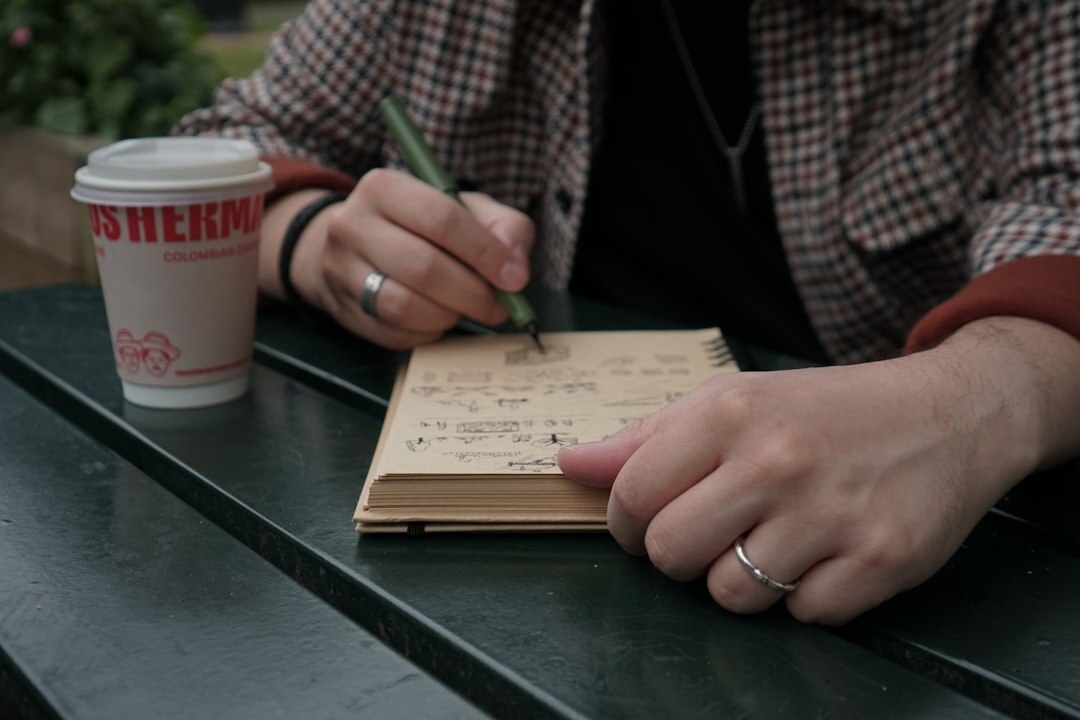 Person writing in a personal journal at a wooden table